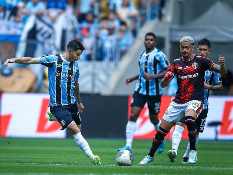 El paraguayo Mathías Villasanti (i), futbolista de Gremio de Porto Alegre, ejecuta un balón en el partido frente al São Paulo por la fecha 36 de la Serie A de Brasil en el estadio Arena do Gremio, en Porto Alegre, Brasil.