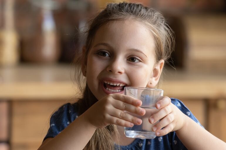 una niña toma un vaso de agua