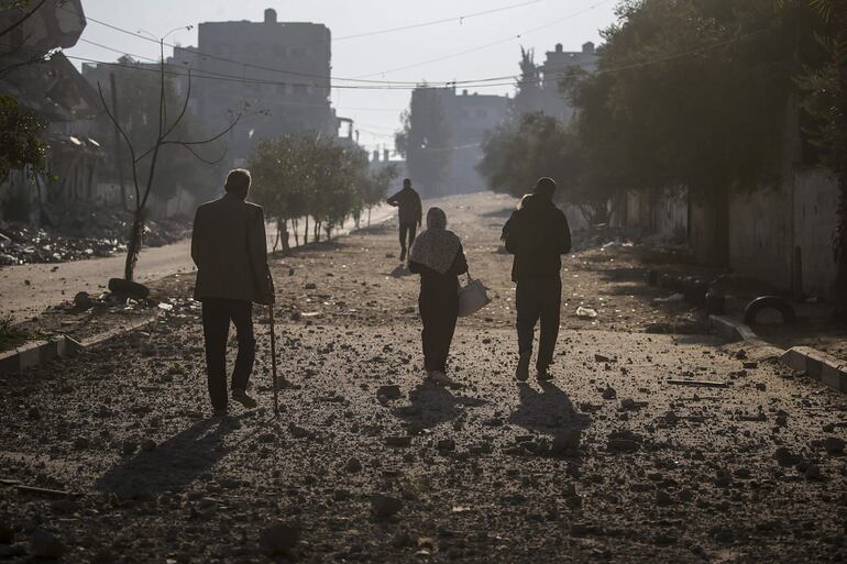 Una familia palestina camina por una calle entre escombros cerca de un edificio destruido tras un ataque aéreo en el campo de refugiados de Al Nuseirat, en el centro de la Franja de Gaza.