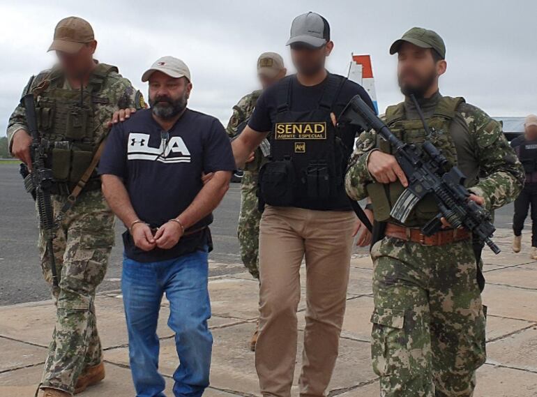 Levi Adriani Felicio, esposado, momentos antes de abordar el avión que lo trasladaría a su último destino antes de ser expulsado a su país.