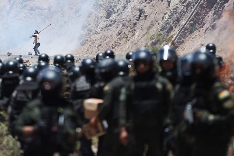 Un hombre se enfrenta con miembros de la Policía Militar Boliviana durante un bloqueo por simpatizantes del expresidente de Bolivia, Evo Morales (2006-2019) este viernes, en Parotani (Bolivia). 