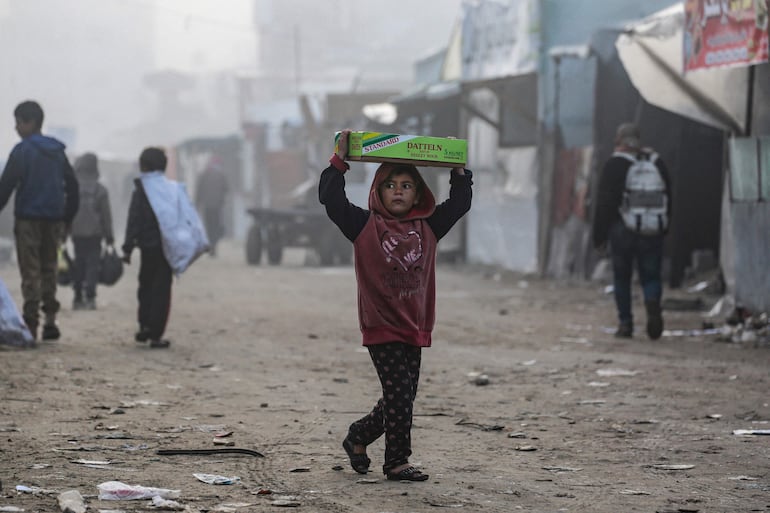 Una niña lleva una caja mientras camina este viernes en Jan Yunis, en el norte de la Franja de Gaza.