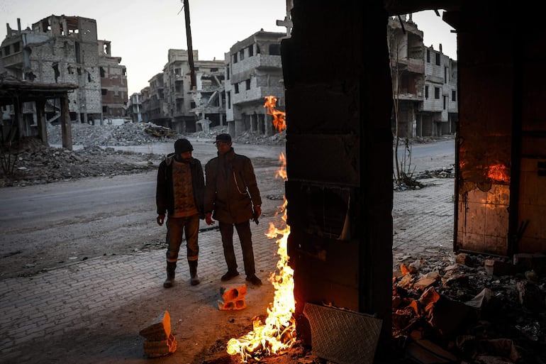 Dos hombres se calientan cerca de una hoguera en una calle del campo de refugiados de Yarmouk, en las afueras de Damasco, Siria, el pasado 19 de diciembre de 2024.