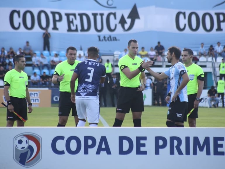 Los jugadores de Sportivo Ameliano y Guaireña saludan a los árbitros en la previa del partido por el fútbol paraguayo 2022 en el Parque del Guairá de la ciudad de Villarrica.