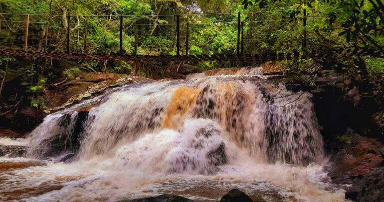 Imponente cortina de agua en el Salto Mirian Mabel con su puente colgante.