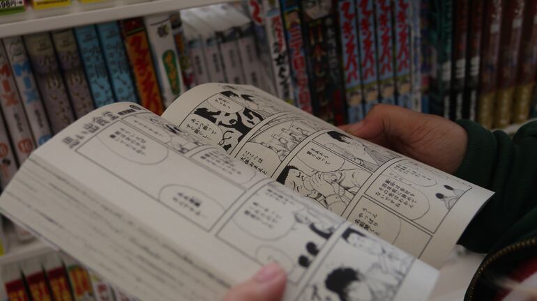 Un hombre hojea una revista de manga.