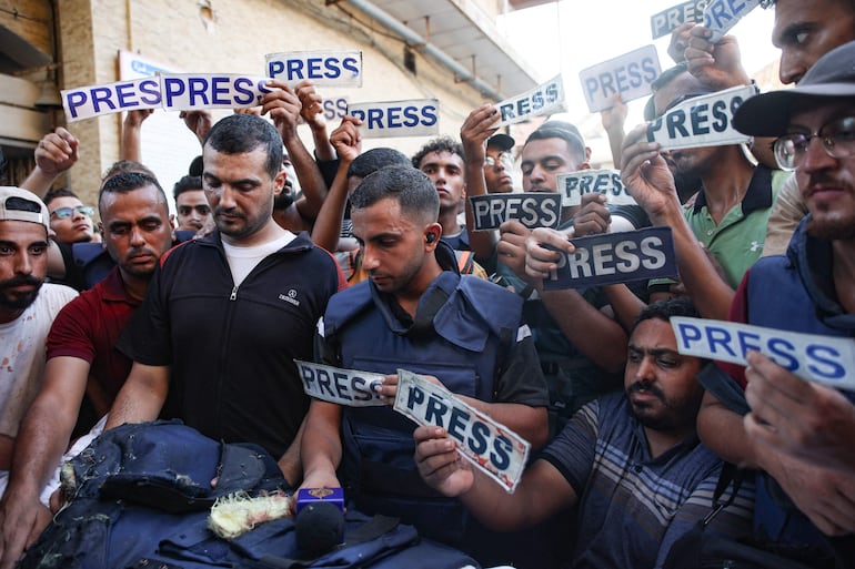 Varias personas con carteles que rezan "prensa" rodean el cuerpo del periodista Ismail al-Ghoul, de Al Jazeera, fallecido junto a su camarógrafo Rami al-Refee en un bombardeo israelí en el campo de refugiados de Al-Shati, en Gaza, el pasado 31 de julio.