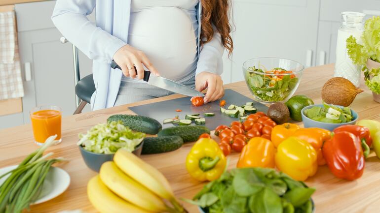 Mujer embarazada cocinando.