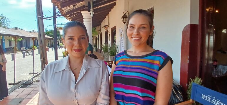 una mujer de camisa blanca con una mujer de blusa con rayas de colores