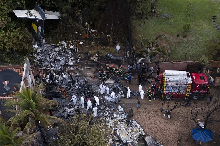 Fotografía aérea que muestra agentes de policía científica de Brasil y bomberos trabajando este sábado, en el sitio donde se estrelló un avión de la aerolínea Voepass en la ciudad de Vinhedo (Brasil). El avión que se estrelló este viernes en el interior del estado brasileño de São Paulo en un accidente en el que murieron sus 62 ocupantes estaba en condiciones regulares de vuelo y no llegó a reportar ninguna emergencia, informaron los responsables por la investigación.