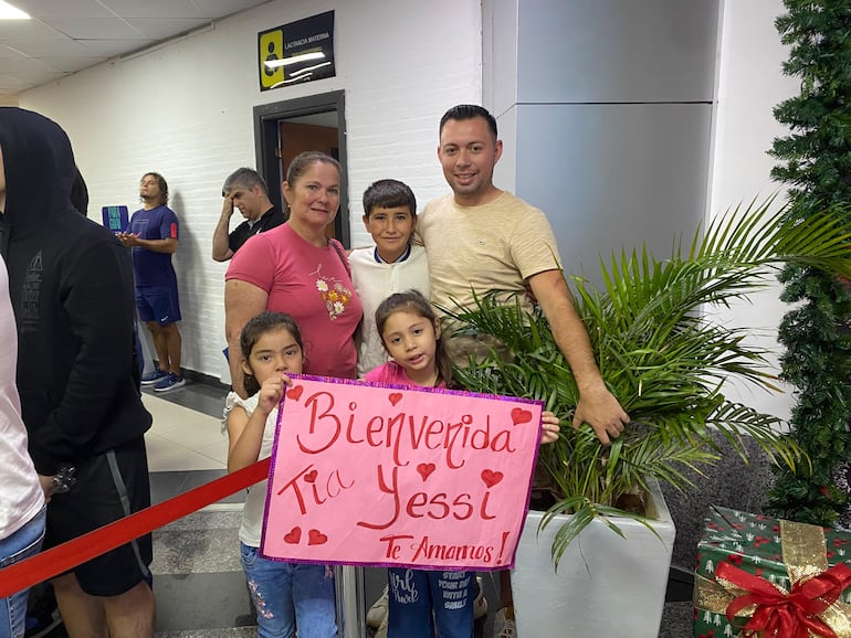 Con un cartel lleno de cariño, una familia espera a su querida "Yessi" en el Aeropuerto Silvio Pettirossi.