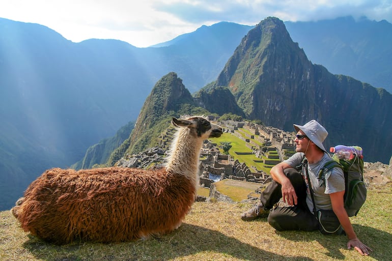 Turista posa con una llama en la Ciudadela de Machu Picchu, Perú, el destino del Camino Inca.