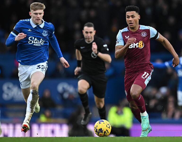 Jarrad Branthwaite (i), zaguero del Everton, corre en procura de dar alcance a  Ollie Watkins, delantero del Aston Villa, que se proyecta con el balón.