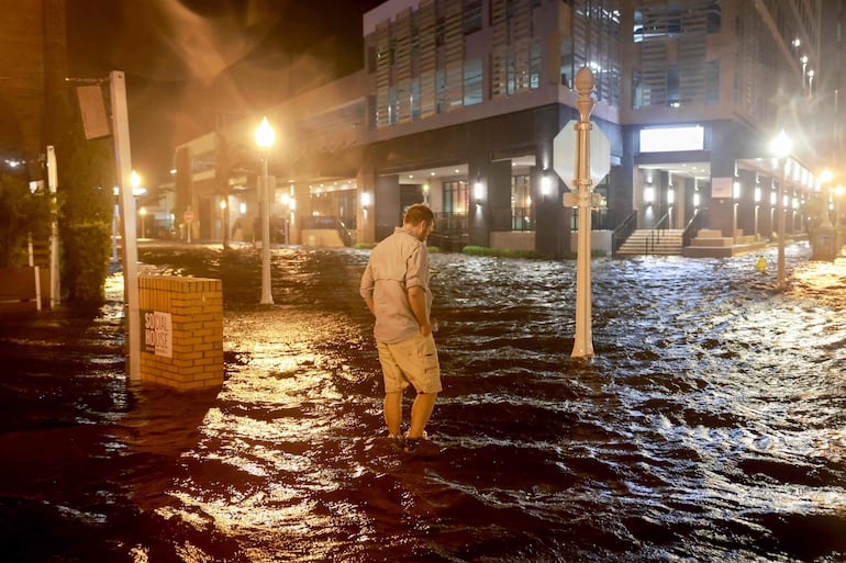 Una persona camina entre las aguas que inundaron la calle después de que el huracán Milton tocara tierra en el área de Sarasota, en Fort Myers, Florida.