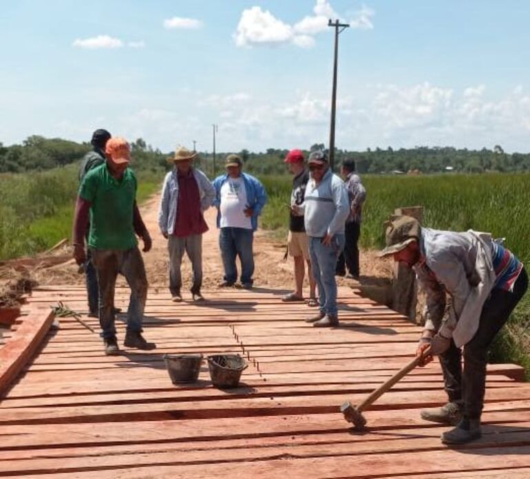 Funcionarios del MOPC y la Municipalidad de San José trabajan en el cambio de las maderas de la pasarela sobre el arroyo Yate´i