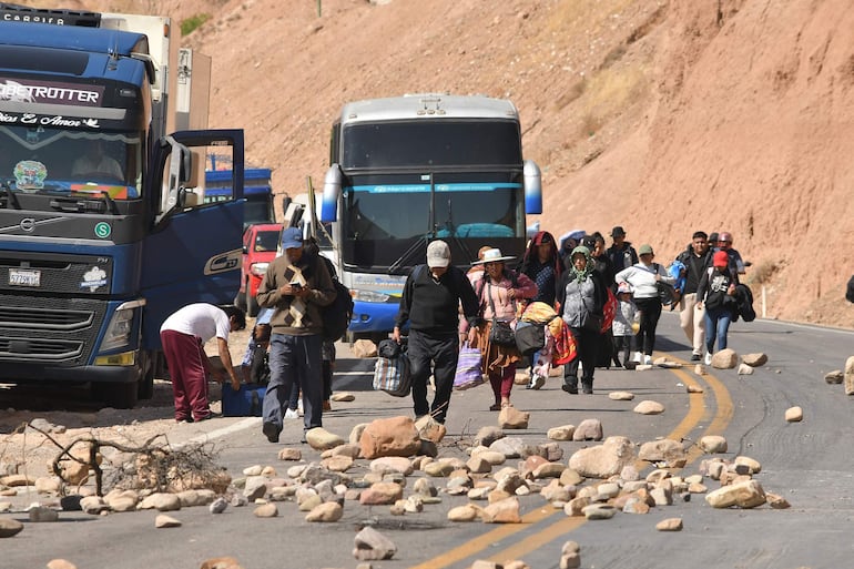 Personas caminan con sus equipajes durante la segunda jornada de bloqueos por seguidores del expresidente Evo Morales (2006-2019). Los simpatizantes de Morales mantienen los bloqueos en defensa del líder oficialista, en respuesta a una investigación de la Fiscalía en su contra por un presunto caso de trata de personas y estupro. EFE/Jorge Ábrego