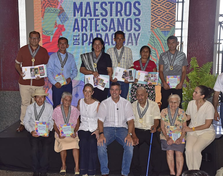 Los maestros y maestras artesanas posan con sus medallas al mérito junto al presidente Santiago Peña, la Primera Dama Leticia Ocampos y la presidenta del IPA, Andrea Vázquez.