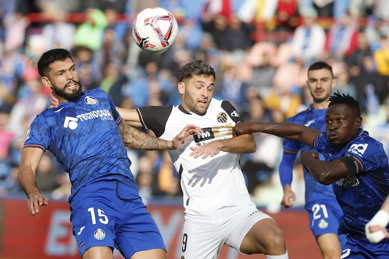 GETAFE (MADRID), 27/10/2024.- El delantero del Valencia Hugo Duro (c) disputa un balón con los defensas del Getafe Omar Alderete (i) y Djené Dakonam (d) durante el partido de la jornada 11 de LaLiga, este domingo en el Estadio Coliseum de Getafe (Madrid). EFE/ Juanjo Martín
