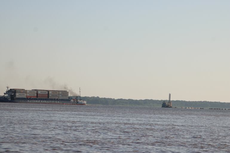 Una embarcación tratando de navegar en la zona más crítica de río Paraguay, a un costado se ve el equipo de draga que está trabajando en la limpieza del río.