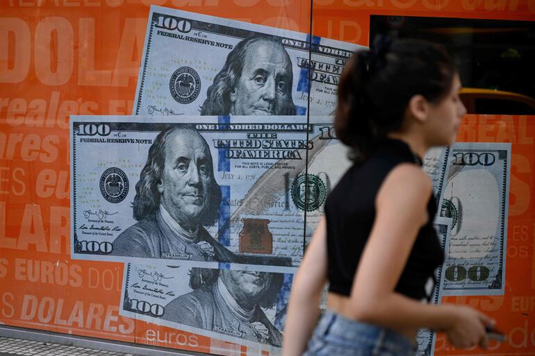 Una mujer pasa junto a un cartel gigante que muestra billetes de dólares, en Buenos Aires, Argentina.