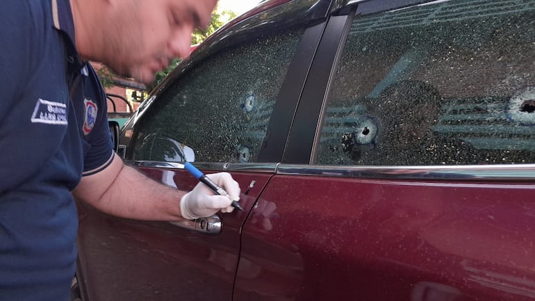 Un oficial de policía verifica los orificios de bala en la camioneta de Mario Aníbal Escobar (funcionario de la Ande), en Pedro Juan Caballero.