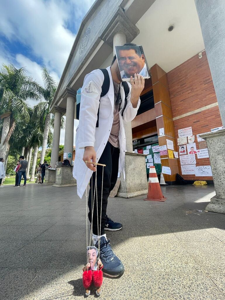 Estudiante de Medicina con un "títere" de Santiago Peña y una "máscara" de Horacio Cartes, presidente de la ANR y líder de Honor Colorado.