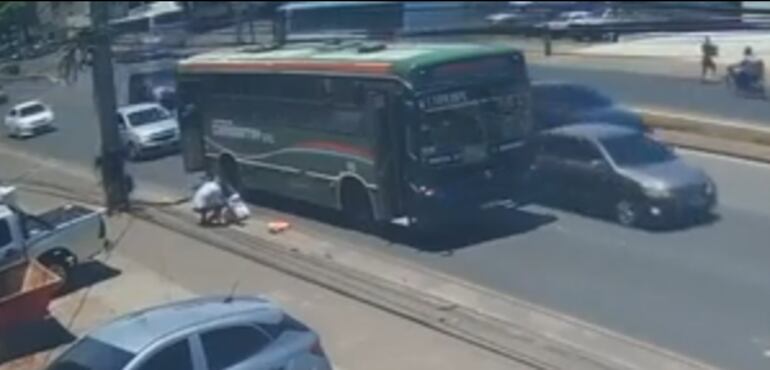 Una persona asiste a la mujer luego de la caída desde el bus en movimiento.