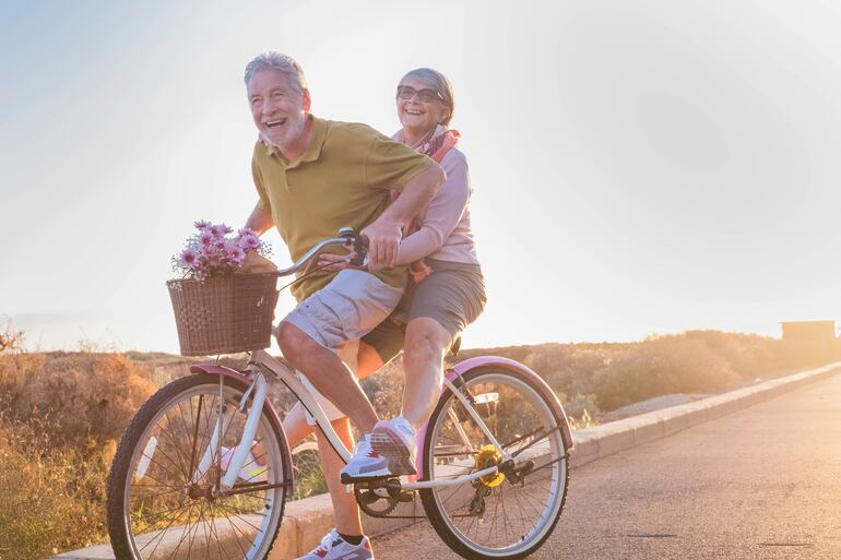 Una pareja de la tercera edad pasea en bicicleta.