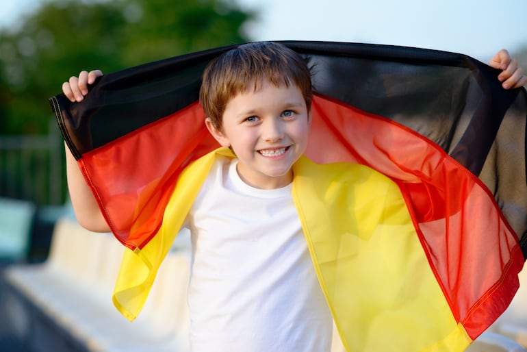 Imagen ilustrativa: un niño sonriente con una bandera de Alemania.