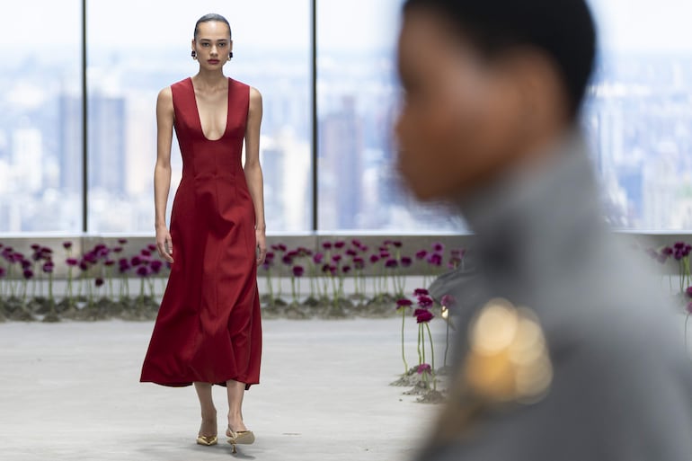 El desfile se enmarcaba en una sala en lo alto de un rascacielos de aspecto industrial, con paredes blancas y unas grandes cristaleras con espectaculares vistas a la ciudad de Nueva York, combinadas con la delicadeza de las peonias de color morado intenso que cubrían el suelo. 
