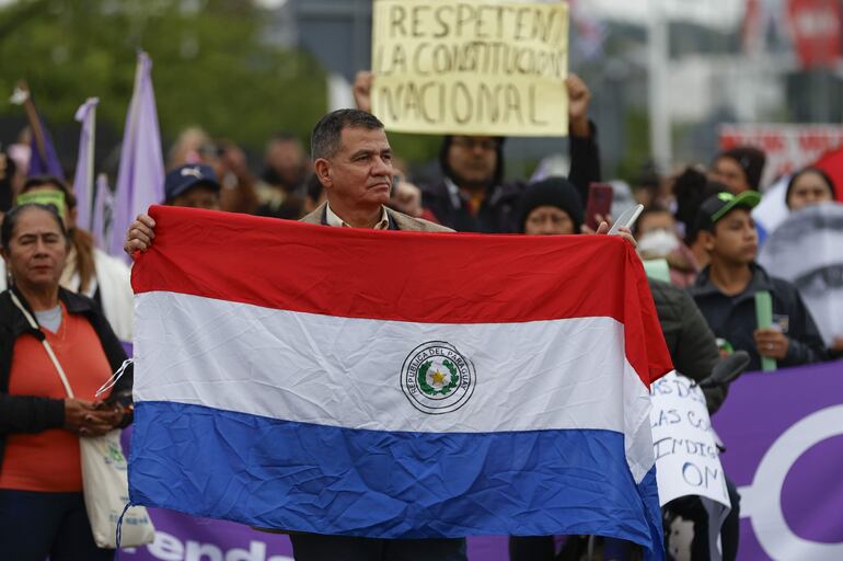 Un activista sostiene una bandera de Paraguay en una protesta contra la violencia y el respeto a la constitución este miércoles, afuera del Centro de Convenciones de la Conmebol donde la Organización de Estados Americanos (OEA) celebra su 54ª Asamblea General, en Luque (Paraguay).