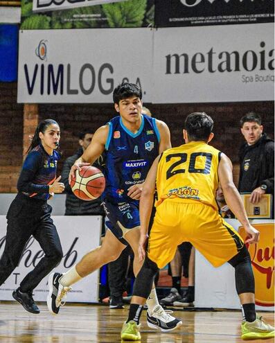 El sanjosiano Juan Medina avanza ante la marca del colono Sebastián Galarza (20), en el juego de anoche donde Deportivo San José se impuso a Colonias Gold por 75-61.