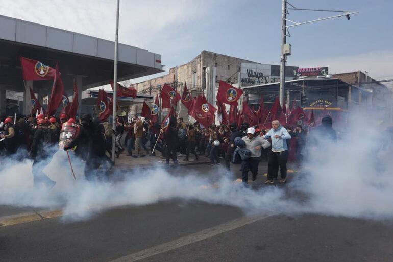 Personas corren luego de ser afectadas por un gas lacrimógeno durante una manifestación, este domingo, en Santiago (Chile). 
