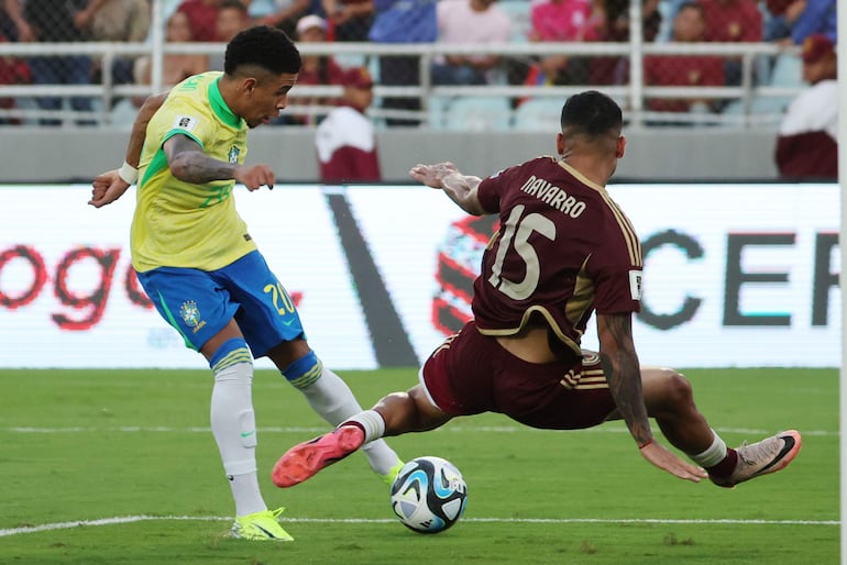 Miguel Navarro (d) de Venezuela disputa el balón con Savinho de Brasil, este jueves durante un partido de las eliminatorias sudamericanas al Mundial de Fútbol 2026, en el estadio Monumental, en Maturín (Venezuela).