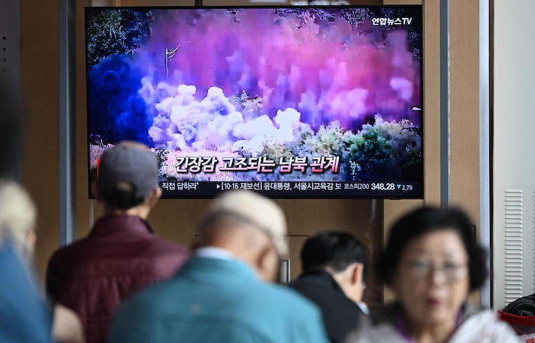 Surcoreanos observan una transmisión de TV en la que muestran la explosión y caída de un puente que unía Corea del Norte con el Sur.