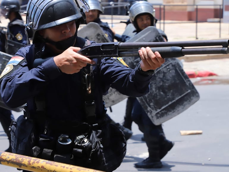 Manifestación contra la aprobación de la ley que crea la Superintendencia de Jubilaciones y Pensiones. Un policía apunta con su arma.