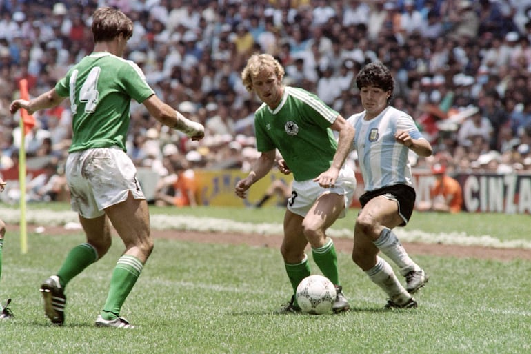 (FILES) Argentina's Diego Maradona (R) fights for the ball with German Andreas Brehme (C) and his teammate Thomas Berthold during the final match of the 1986 Football World Cup Federal Republic of Germany vs. Argentina on June 29, 1986 at Mexico City. Andreas Brehme, who scored from the penalty spot to seal victory for West Germany against Argentina in the 1990 World Cup final, died overnight into February 20, 2024 at the age of 63, his former club Bayern Munich said. (Photo by AFP)