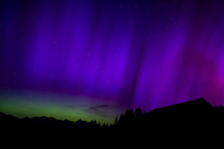 Las luces del norte iluminan el cielo sobre las montañas en Le Col des Mosses, en Suiza. 