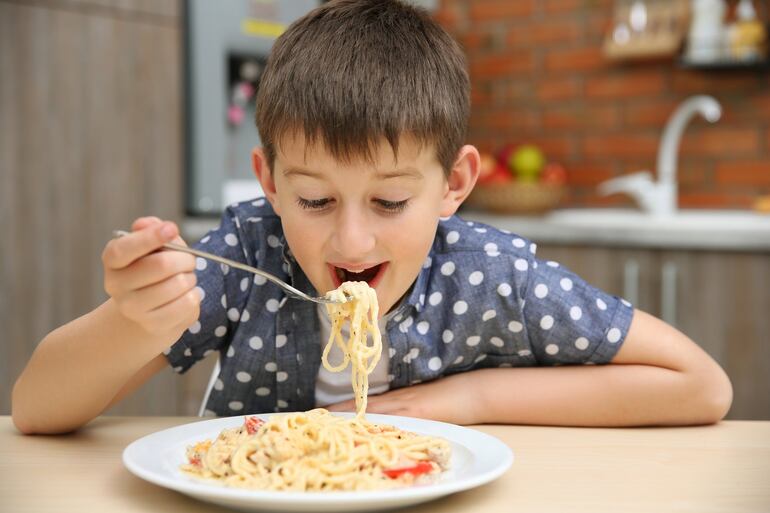 Niño cenando pasta.