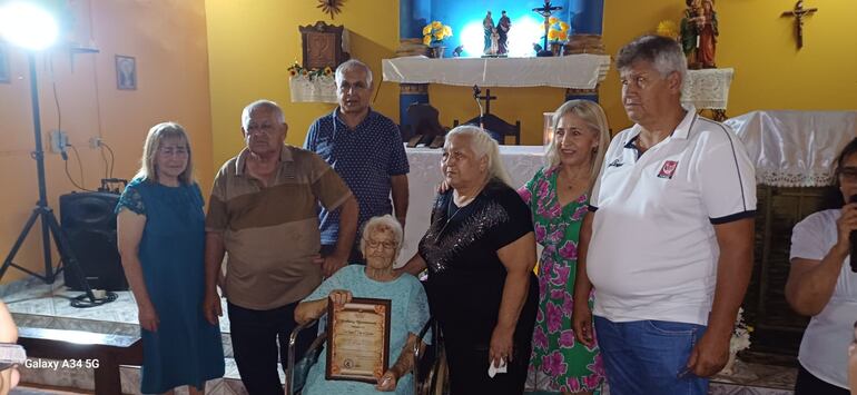 La abuela Teófila Cáceres recibió un reconocimiento por los integrantes de la Capilla Sagrada Familia.