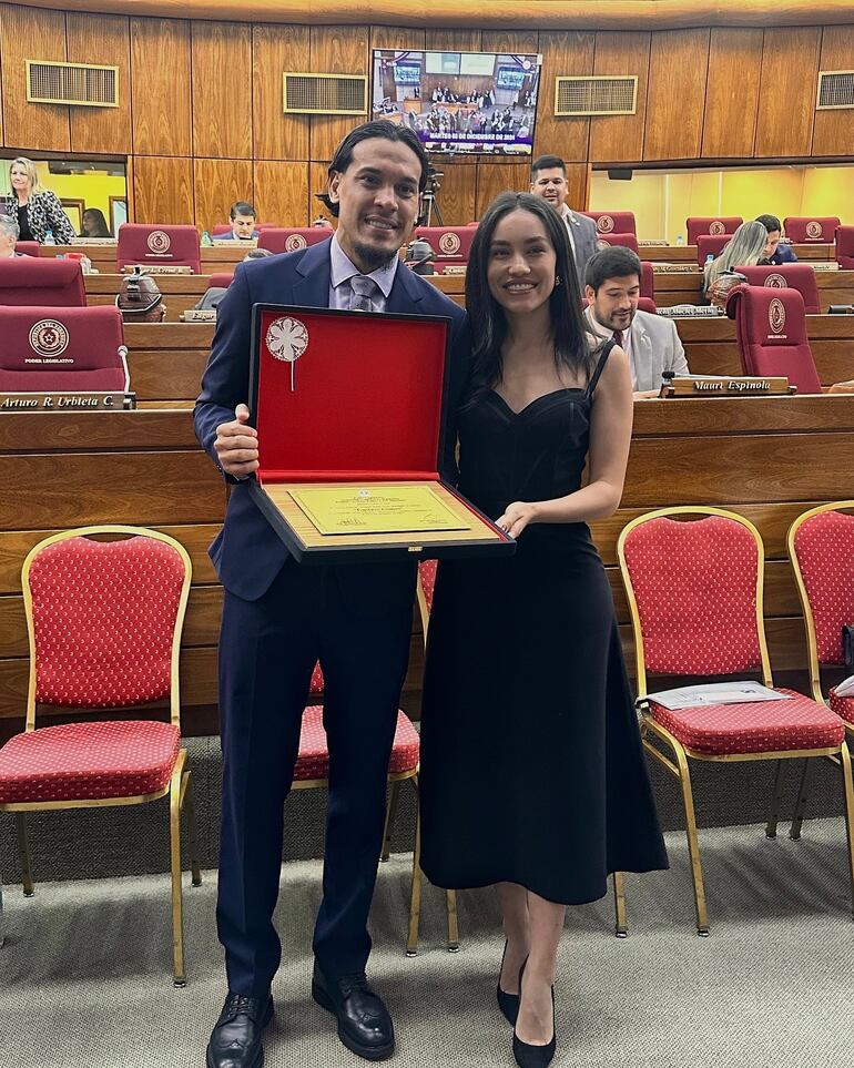 Gustavo Gómez mostrando el reconocimiento que recibió en la Cámara de Diputados, acompañado de su esposa Jazmín Torres. (Instagram/Jazmín Torres)