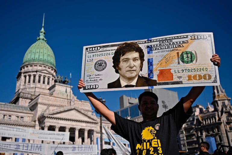 Un partidario del presidente de Argentina, Javier Milei, muestra un cartel con un billete de cien dólares con una imagen del mandatario en las afueras del Congreso.