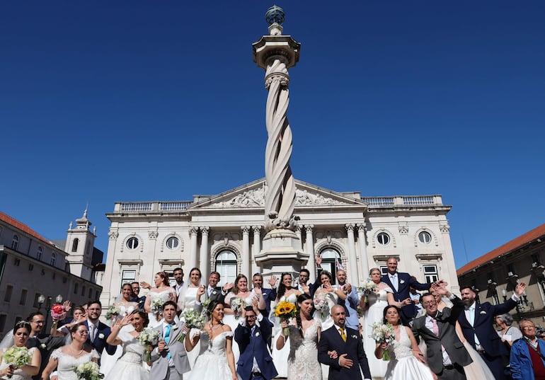 Las parejas recién casadas posan para una foto grupal después de casarse durante una ceremonia tradicional, en la Catedral de Lisboa, en las afueras del Ayuntamiento de Lisboa. 
