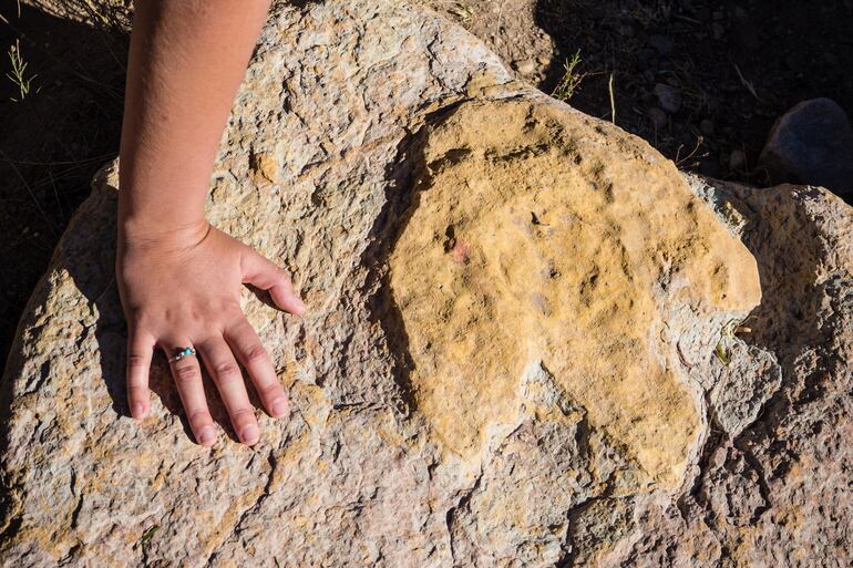 Mano al lado de huella de dinosaurio en Torotoro, Bolivia.