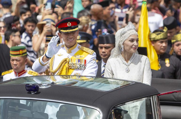 Recién casados. El príncipe Abdul Mateen y Yang Mulia Anisha Rosnah saludan desde su Rolls-Royce.