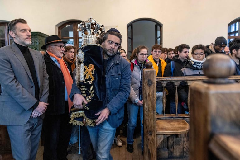 Un hombre lleva una Torá ante el Gran Rabino de Francia, Haim Korsia, quien realizará una oración con un grupo de estudiantes de secundaria de Francia en la sinagoga de Oswiecim, en el sur de Polonia, el 5 de diciembre de 2024. Esther Senot, sobreviviente del Holocausto, ahora de 97 años, tenía 15 años cuando llegó al campo de concentración nazi de Auschwitz-Birkenau en septiembre de 1943. Ahora ha regresado para contar su historia a un grupo de casi un centenar de estudiantes de secundaria de Francia.