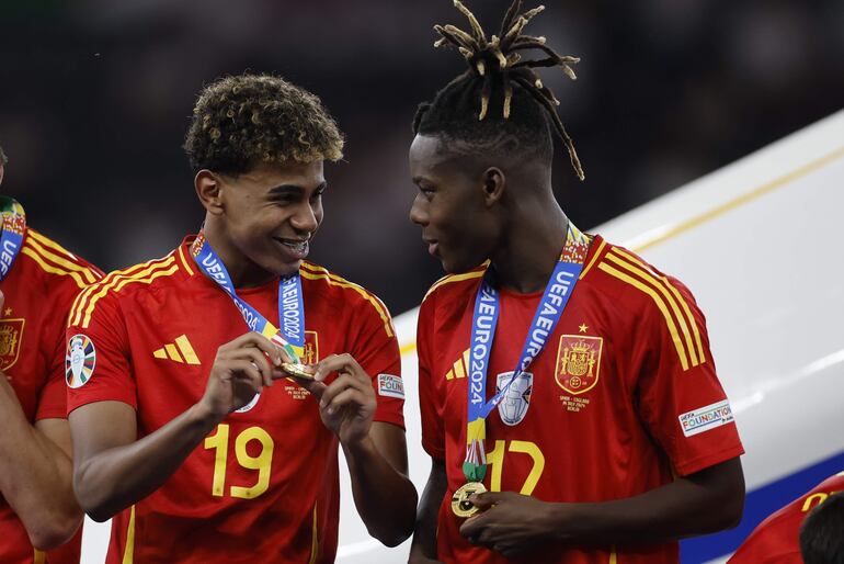 Lamine Yamal (i) y Nico Williams con las medallas de campeón de la Eurocopa 2024 después de superar en la final a Inglaterra en el estadio Olímpico, en Berlín, Alemania. 
