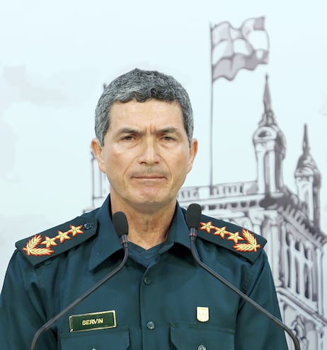 Un hombre adulto de cabello cano vestido como militar frente a dos micrófonos.