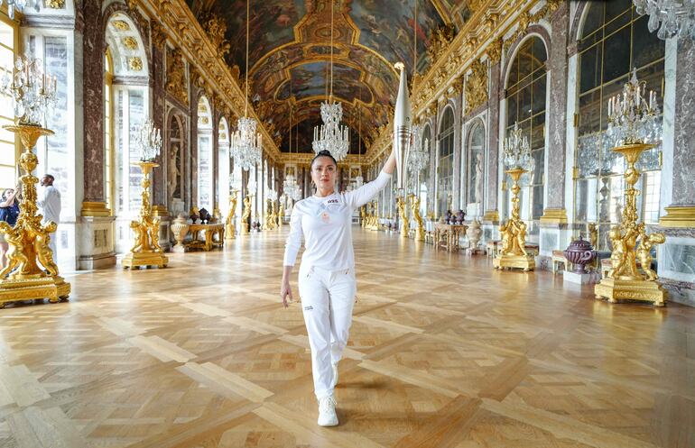 La actriz mexicoamericana Salma Hayek camina con la antorcha olímpica como parte del relevo de la antorcha de los Juegos Olímpicos de París 2024 en el Palacio de Versalles. (Photo by Laurent Vu / Paris 2024 / AFP)