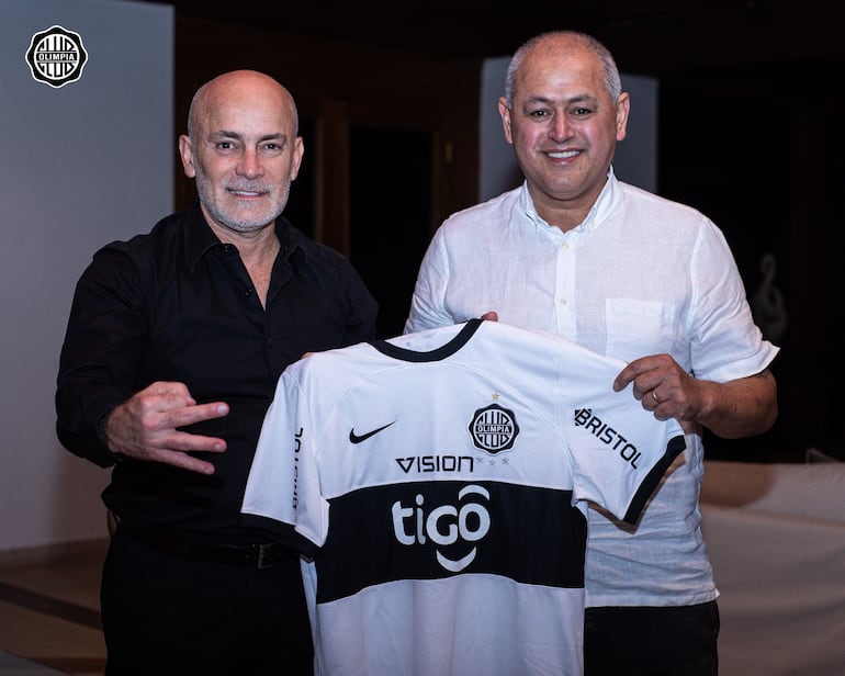 Miguel Cardona, presidente de Olimpia, y Francisco Arce (d) con la camiseta del club después de firmar el contrato para la asunción del entrenador.